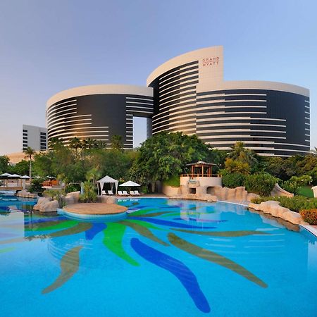 Grand Hyatt Dubai Hotel Exterior photo The photo shows a modern architectural structure, likely a hotel or resort, characterized by two circular buildings with a sleek, contemporary design. The buildings are black and white with horizontal stripes and appear to have large windows. In the 