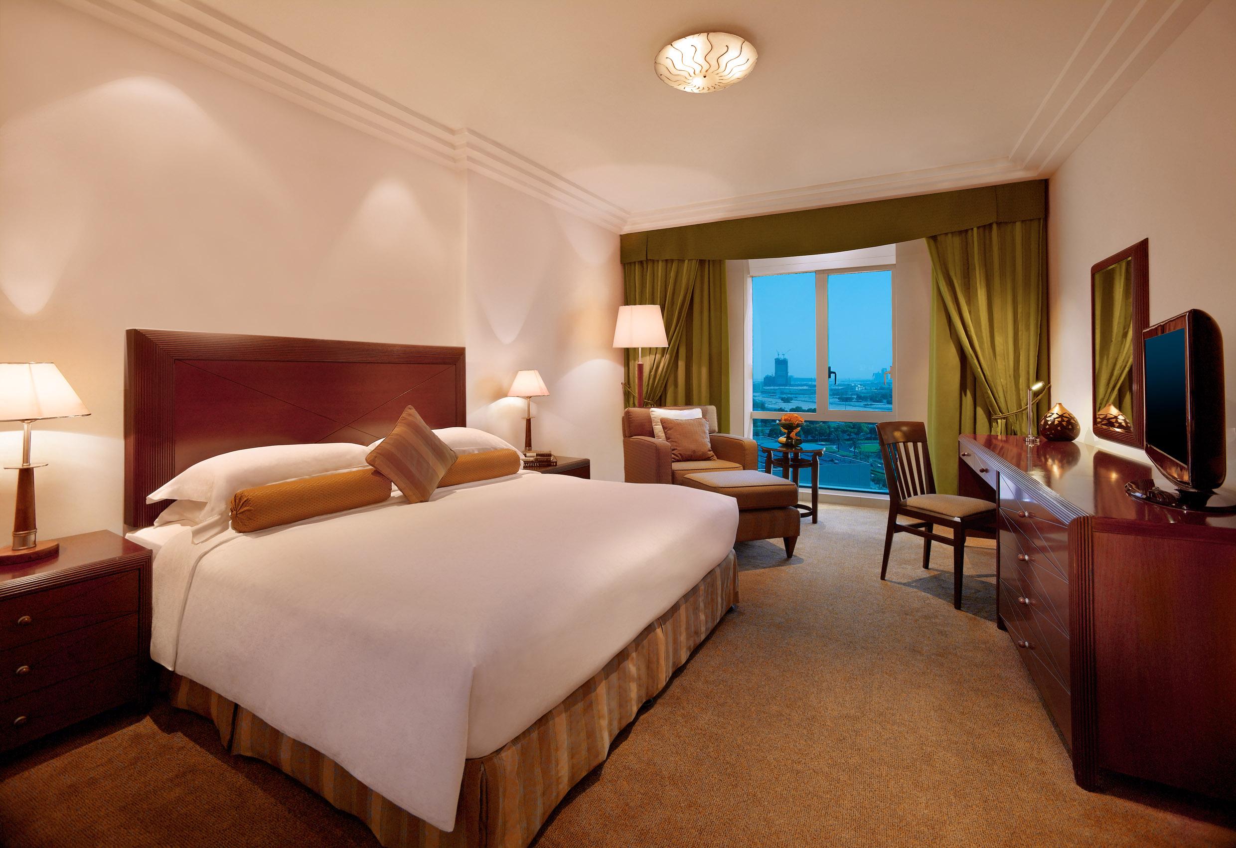 Grand Hyatt Dubai Hotel Exterior photo The photo shows a well-furnished hotel room. It features a large bed with a light-colored comforter and decorative pillows. The walls are painted in a soft color, and there are lamps on either side of the bed. A cozy seating area is present, which in