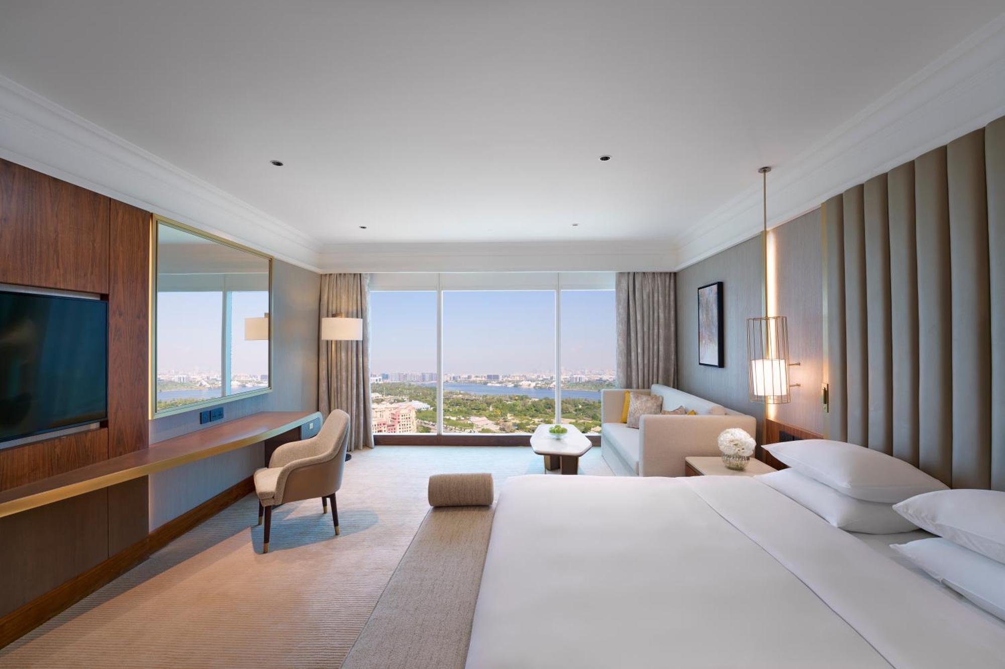 Grand Hyatt Dubai Hotel Exterior photo The photo depicts a modern hotel room featuring a spacious and elegantly designed interior. Key elements include:

- A large bed with crisp white linens, positioned against a wall.
- A comfortable chair and a small side table strategically placed nea