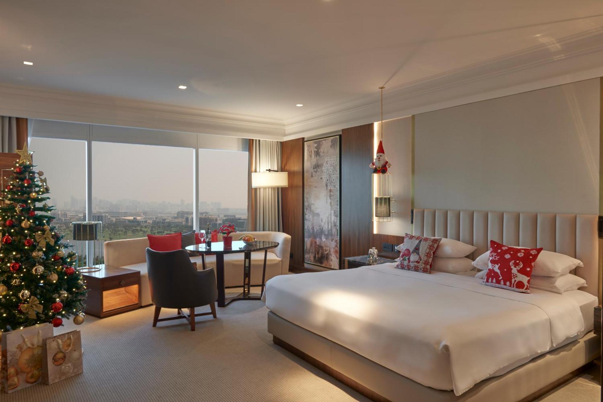 Grand Hyatt Dubai Hotel Room photo The photo depicts a modern hotel room. It features a spacious layout with a large bed placed against a headboard. The bedding includes decorative pillows. To one side, there's a seating area with a small table and two chairs, ideal for lounging. A Ch