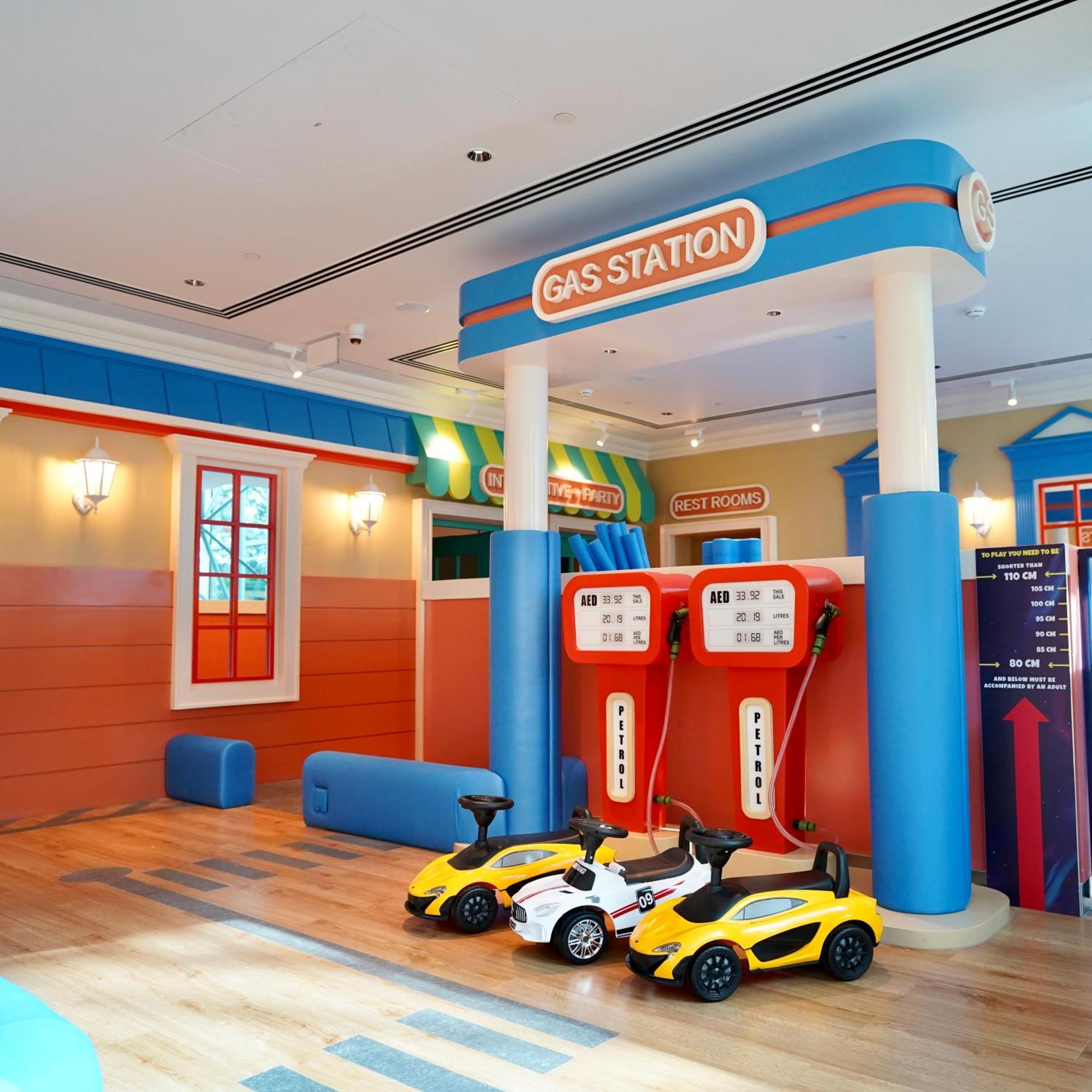 Grand Hyatt Dubai Hotel Exterior photo The photo shows a brightly colored play area designed to resemble a gas station. There are two large gas pumps with a "GAS STATION" sign above them, set against a cheerful backdrop. The walls are painted in vibrant colors, with features like windows 