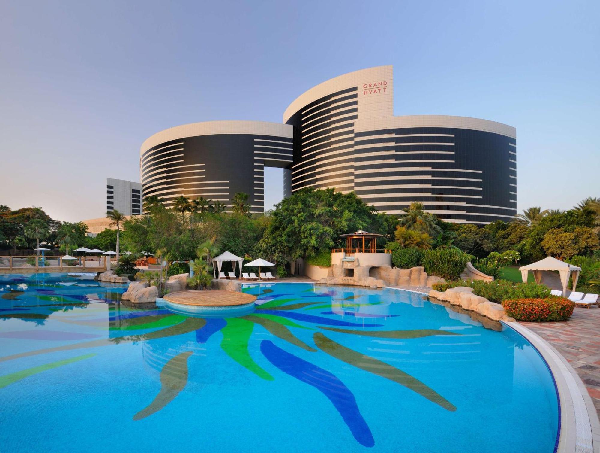 Grand Hyatt Dubai Hotel Exterior photo The photo shows a modern architectural structure, likely a hotel or resort, characterized by two circular buildings with a sleek, contemporary design. The buildings are black and white with horizontal stripes and appear to have large windows. In the 