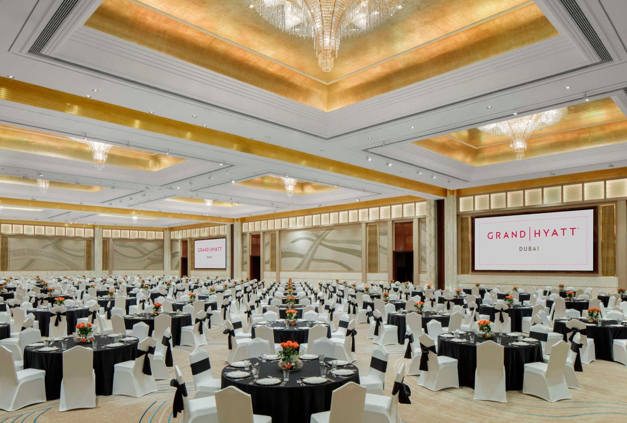 Grand Hyatt Dubai Hotel Exterior photo The image shows a large banquet hall set up for an event at the Grand Hyatt. The room is spacious with elegantly designed decor, featuring high ceilings and chandeliers. Numerous round tables are arranged throughout the space, each covered with black