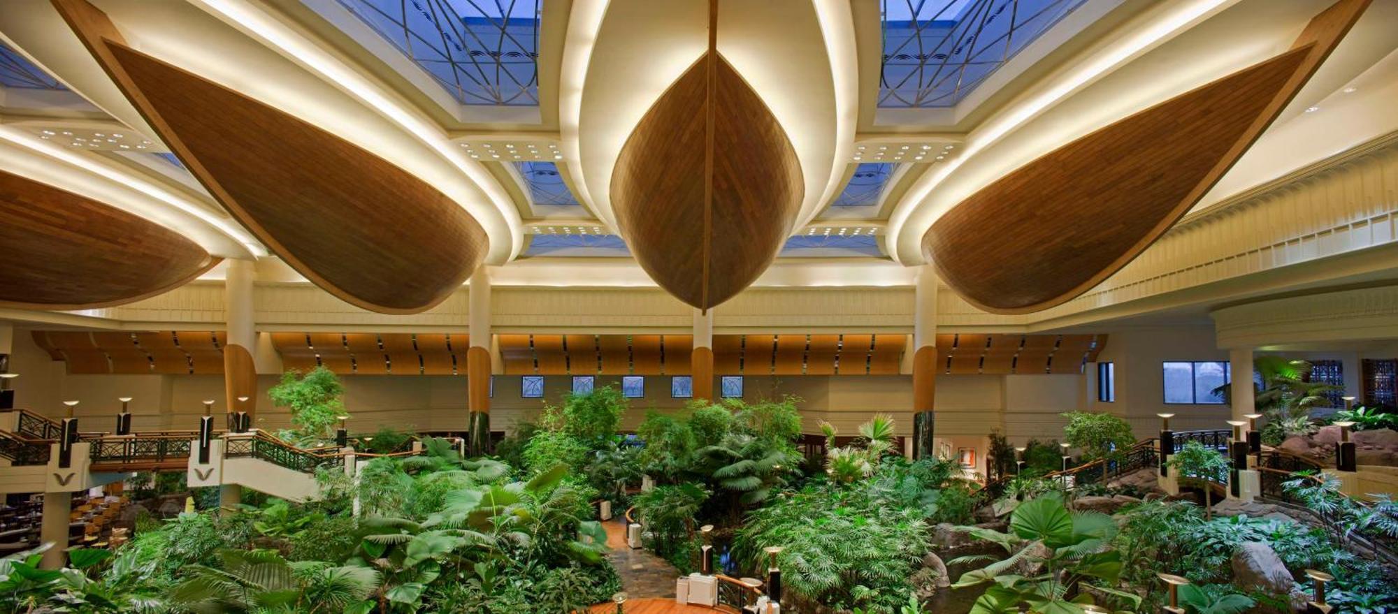 Grand Hyatt Dubai Hotel Exterior photo The photo showcases an indoor space that features a lush, tropical garden with abundant greenery, including various plants and trees. The architecture above is striking, with large, curved wooden structures reminiscent of boat hulls, which adds a uni