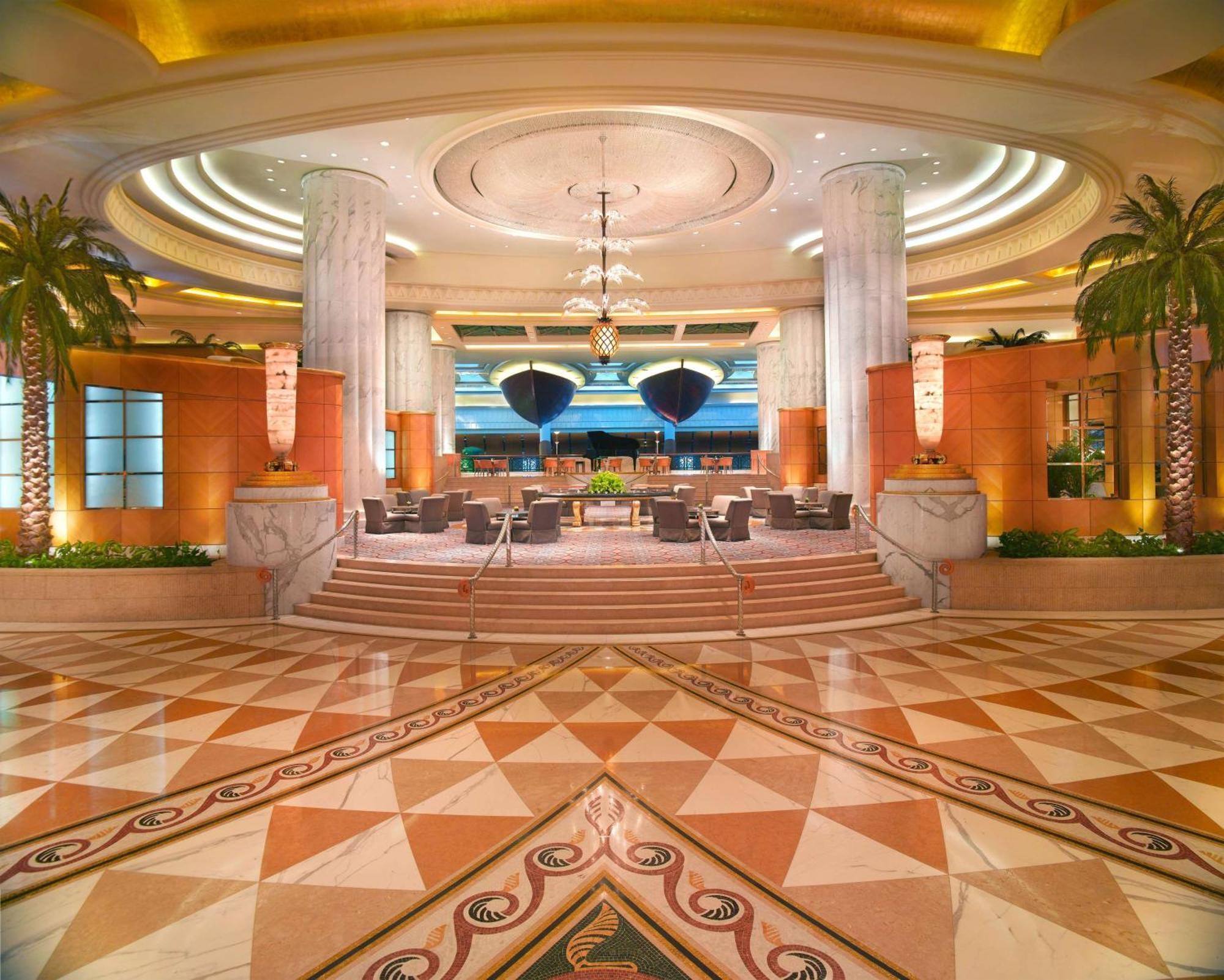 Grand Hyatt Dubai Hotel Exterior photo The photo depicts a luxurious hotel lobby. The space features high ceilings with elegant lighting and intricate architectural details. Tall columns stand prominently, and there are stylish seating arrangements visible. The floor is adorned with a geo